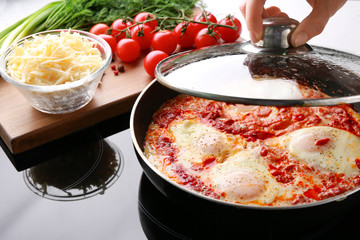 Woman cooking eggs in purgatory on stove