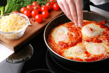 Woman cooking eggs in purgatory on stove