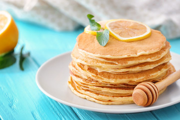 Plate with delicious pancakes and lemon on table