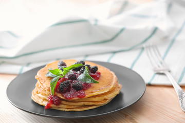 Plate with delicious pancakes on table