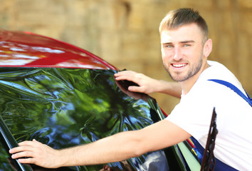 Worker applying tinting foil onto car window