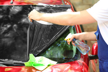 Worker applying tinting foil onto car window