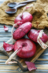 Sweet red onions on an old wooden board.