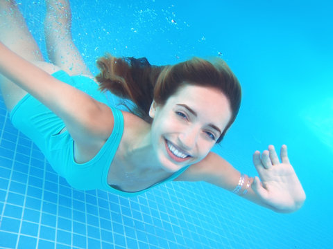 Beautiful Young Woman Swimming Under Water In Pool