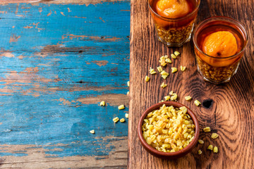 Mote con huesillo. Traditional Chilean drink made from cooked husked wheat and dried peach on wooden board, rustic blue background
