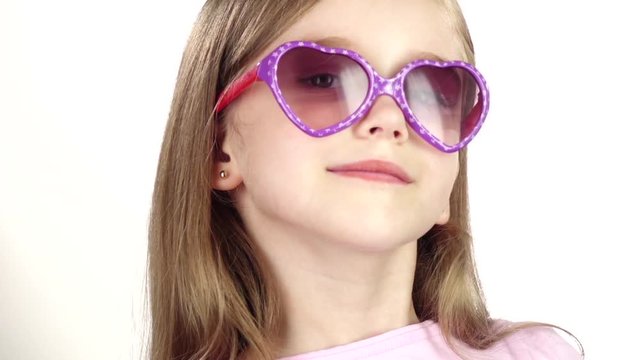 Baby posing for video cameras with glasses. White background. Close up. Slow motion