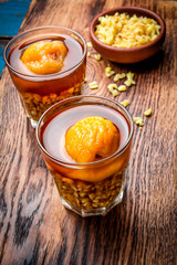 Mote con huesillo. Traditional Chilean drink made from cooked husked wheat and dried peach on wooden board, rustic blue background
