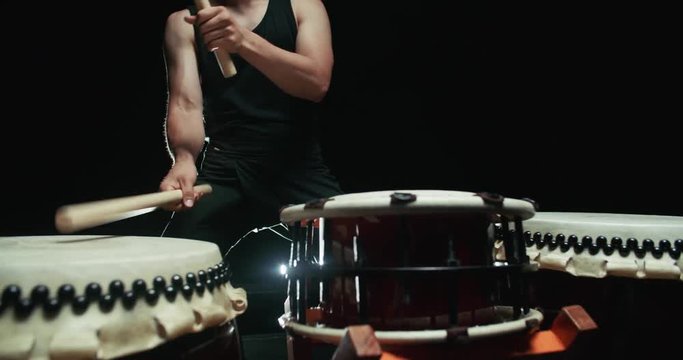 performance of Taiko , Asian male drummer in black clothes, beats a rhythm on three Japanese drums