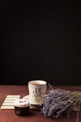 Lavender with cup of tea and cake on the black background