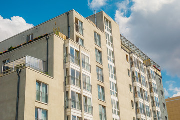 Fototapeta premium modern apartment building with yellow facade and fluffy clouds