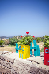 Blooming red geranium in multicolored pots stands on a stone wall in the street, view at midday