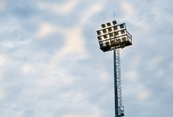 High mast illuminated sports stadium on blue sky background