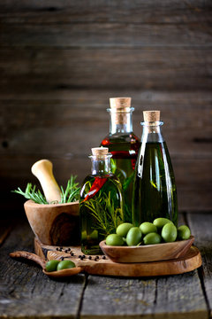 Organic olive oil with spices and herbs on an old wooden background. Healthy food.
