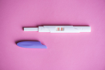 Positive pregnancy test on pink background 