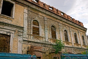 старый разрушенный дом из коричневого кирпича с заколоченными окнами