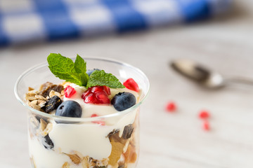 Cup of breakfast healthy muesli with blueberries, seeds of pomegranate and yogurt.