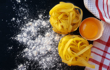 Homemade tagliatelle pasta with eggs on dark board