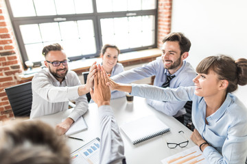 Happy business team giving high five in office.