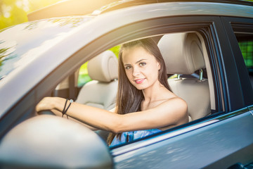 Beautiful young woman sitting in the interior of a new car with a smile.