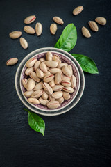 Pistachios in shell on blue plate over black slate background, top view