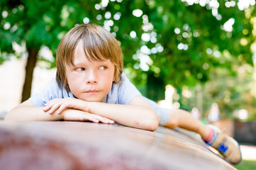portrait of sad dreaming little boy 7 years old outdoors