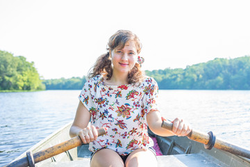 Happy smiling young woman rowing boat on lake in Virginia during summer - Powered by Adobe
