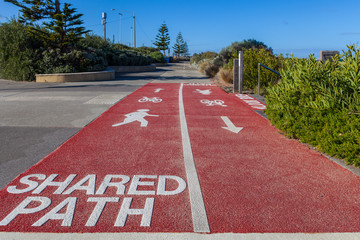 Shared Path sign written on footpath for cyclists and pedestrians with bicycle, walking person, and arrow signs