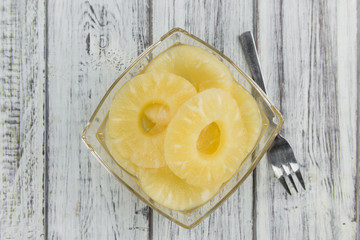 Portion of Preserved Pineapple Rings on wooden background, selective focus