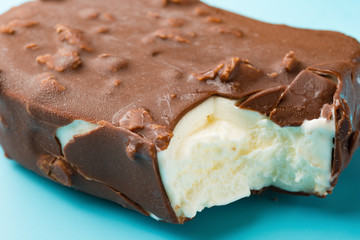 chocolate outer ice cream starts melting with a bite close up on a blue background
