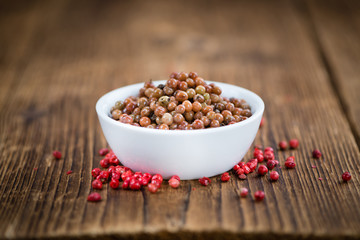 Portion of Pink Peppercorns (preserved) on wooden background, selective focus