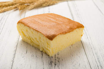 Fototapeta na wymiar sponge cake with wheat on white wood background