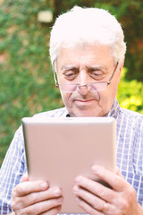 Obraz premium Old man using digital tablet.