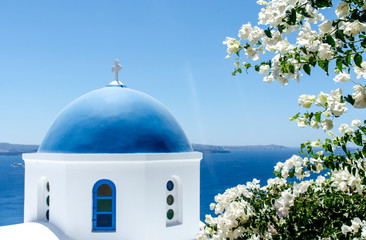 Fototapeta na wymiar Greek church with white flowers overlooking ocean