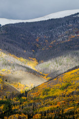 sunlight peaking through a cloud and light hitting the side of a mountain during fall in Colorado