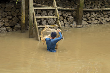 Fisherman is preparing nets to trap fish in the river.