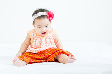 Portrait of adorable baby sitting on a white floor  with head band