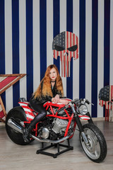 Young attractive woman dressed in leather sitting on a motorcycle in the studio.