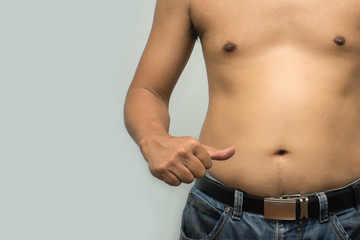 Asian fat man has cholesterol . He shows excess fat of the tummy. By pointing at the his tummy. / Photo concept: fat, belly, obesity, cellulite