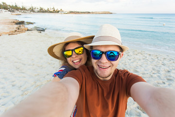 Happy traveling couple making selfie sea background , sunny summer colors, romantic mood. Stylish sunglasses, straw hat. Happy laughing emotional faces.