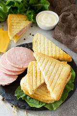 Pressed and toasted classic double sandwich with ham and cheese on a gray stone or slate background.