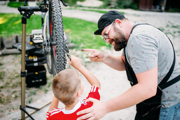 Bicycle mechanic show bike to young boy 