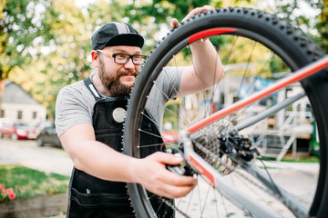 Bicycle repairman works with bike wheel