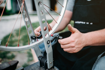 Male person adjusts bike spokes and wheel