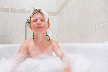 little child is washing her hair in bath