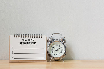 New year's resolution on a notebook and alarm clock on wood table, Copy space
