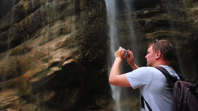 tourist taking pictures of the chegem mountain waterfall