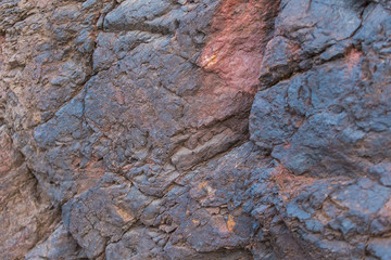 Iron ore texture closeup - natural minerals in the mine. Stone texture of open pit. Extraction of minerals for heavy industry - the texture of the rock containing iron ore and copper.