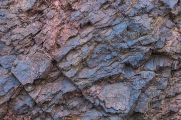 Iron ore texture closeup - natural minerals in the mine. Stone texture of open pit. Extraction of minerals for heavy industry - the texture of the rock containing iron ore and copper.