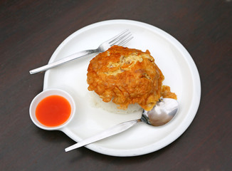 An omelet is a dish made from beaten eggs quickly cooked with butter or oil in a frying pan. served with steamed rice on plate that is Thai Style Fast food.