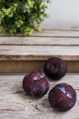 three black plums on the wooden bench 